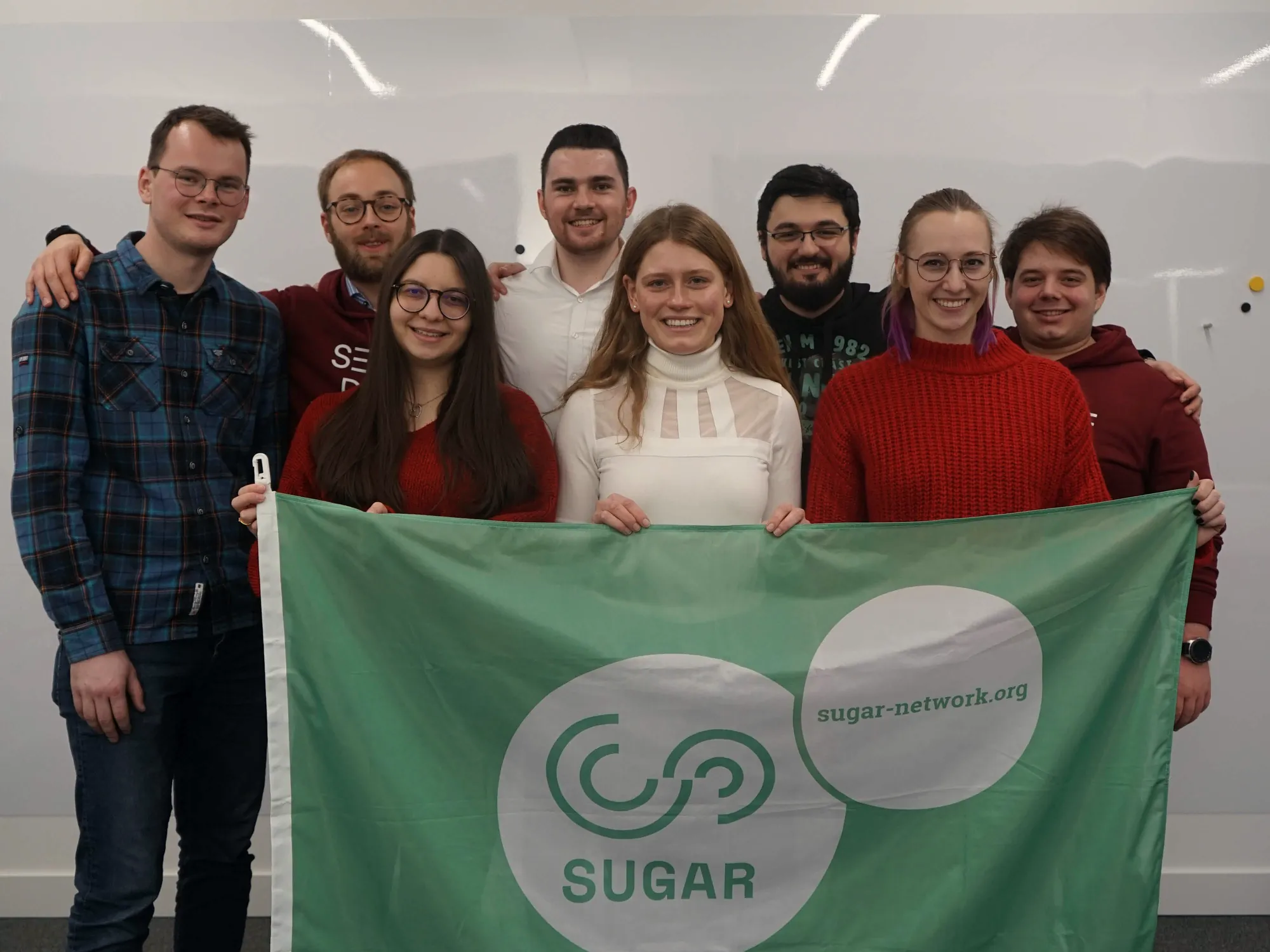 A student team holds up a green SUGAR flag