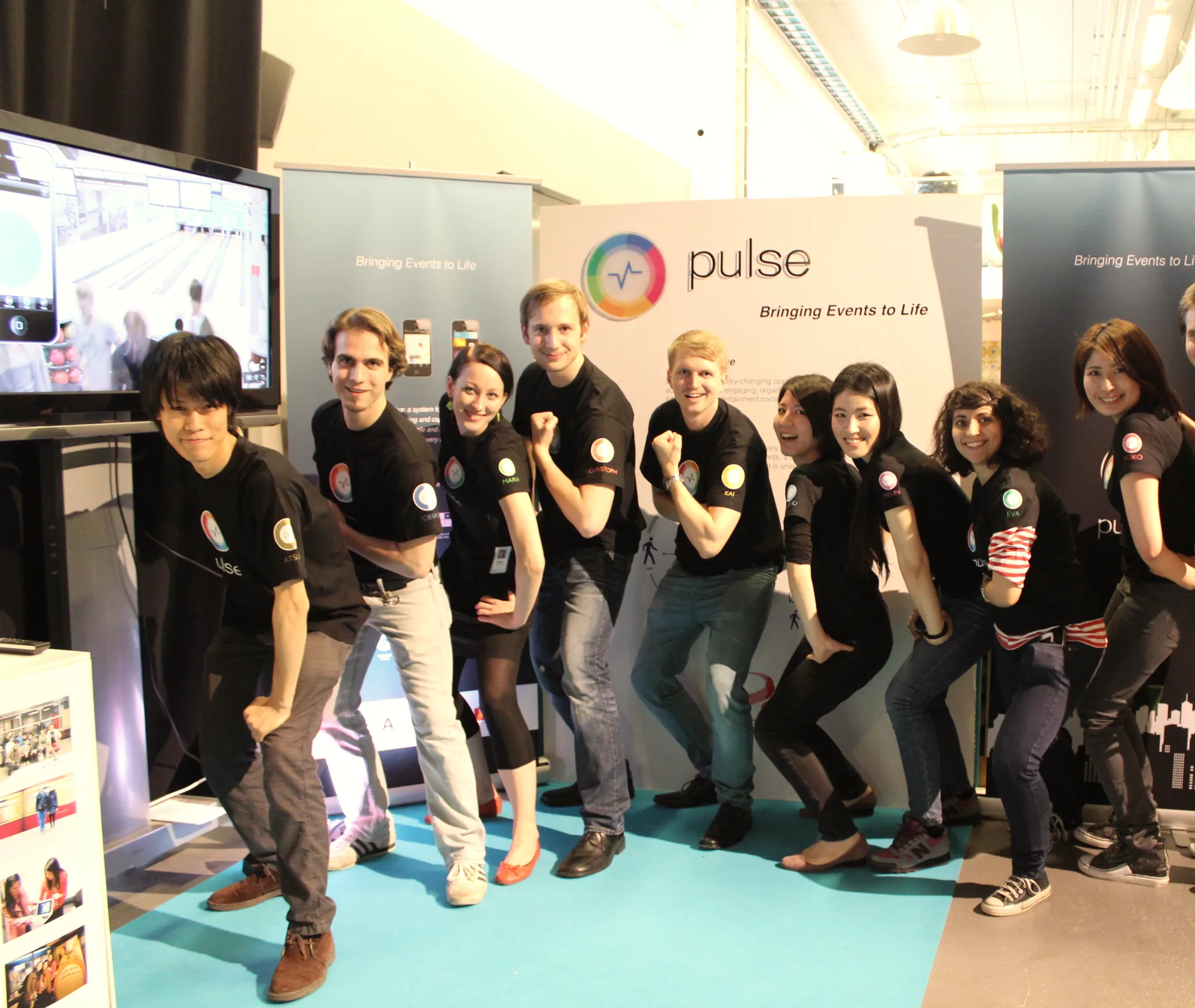 A student team in matching black T-shirts strikes a playful pose at its Expo booth