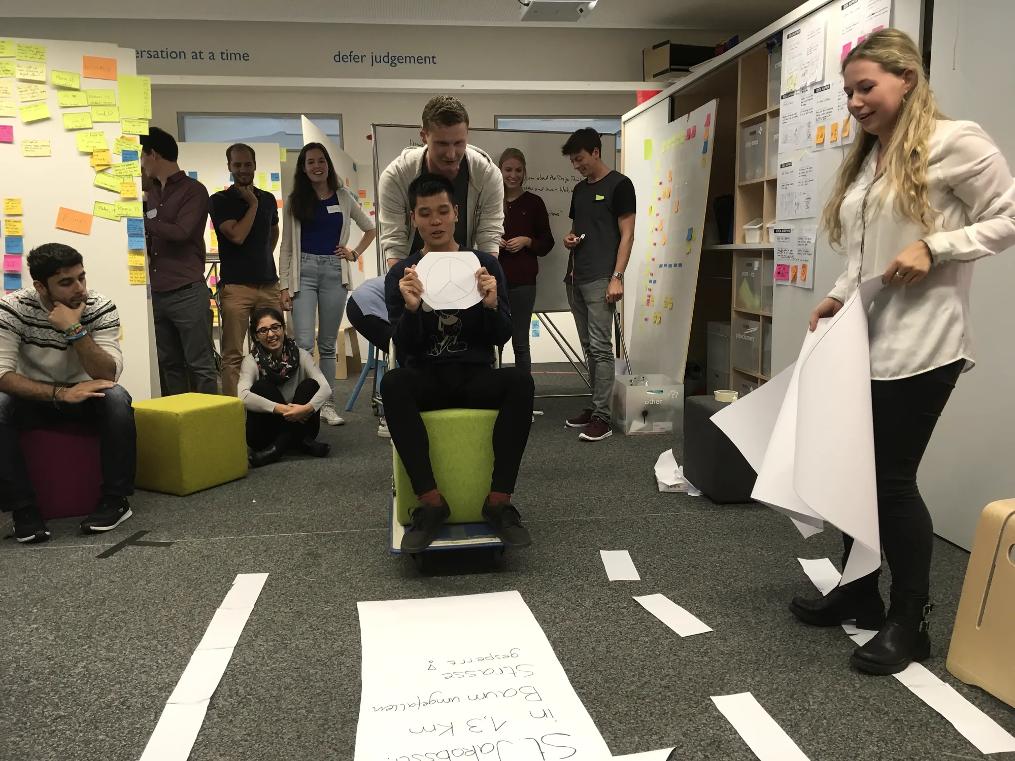 Bodystorming: a student on a chair rides along a road taped to the floor while others watch and play along